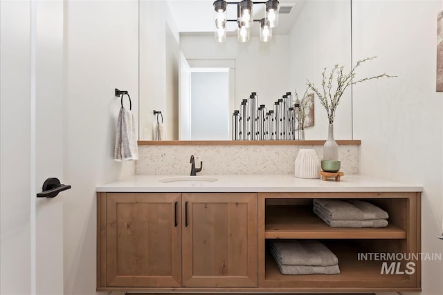 bathroom with vanity, tasteful backsplash, and an inviting chandelier