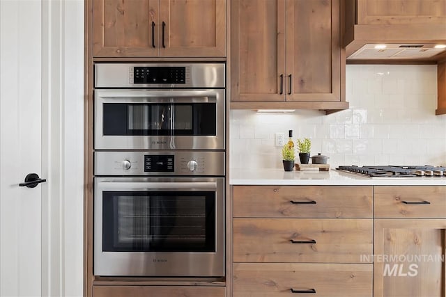 kitchen featuring range hood, appliances with stainless steel finishes, and tasteful backsplash