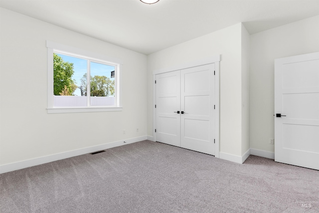 unfurnished bedroom with a closet and light carpet