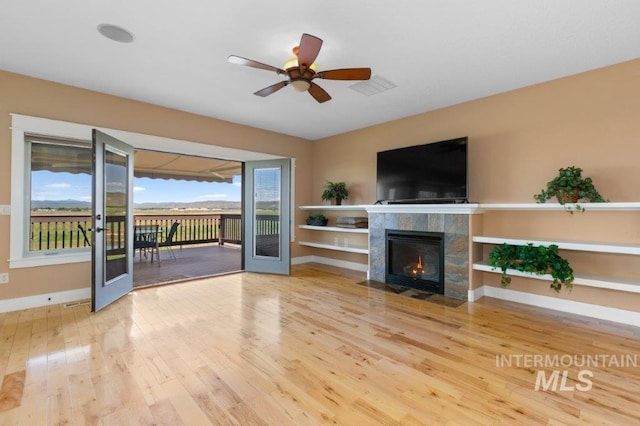 2600 W S Slope Rd, Emmett, ID 83617 - unfurnished living room featuring wood finished floors, a tiled fireplace, baseboards, and ceiling fan