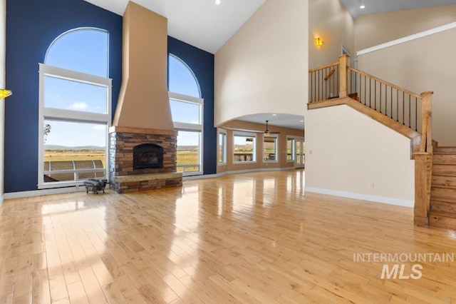 2600 W S Slope Rd, Emmett, ID 83617 - unfurnished living room featuring high vaulted ceiling, stairway, a fireplace, wood finished floors, and recessed lighting