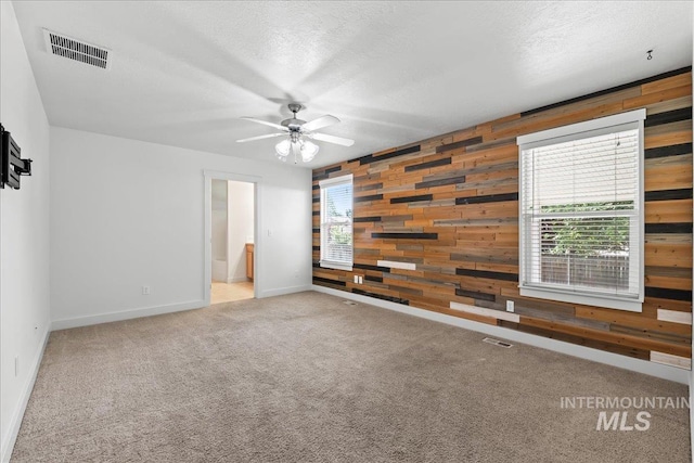 6311 S Solar Way, Boise, ID 83709 - empty room with wood walls, a ceiling fan, baseboards, carpet, and a textured ceiling