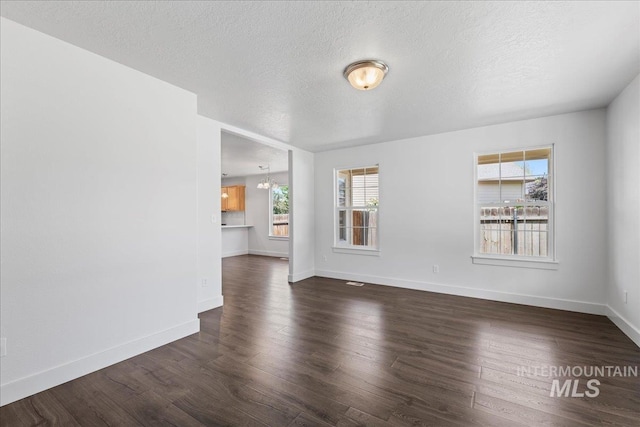 6311 S Solar Way, Boise, ID 83709 - unfurnished living room featuring healthy amount of natural light, a textured ceiling, dark wood finished floors, and a chandelier