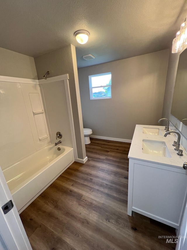 full bathroom featuring a sink, toilet, baseboards, a textured ceiling, and  shower combination