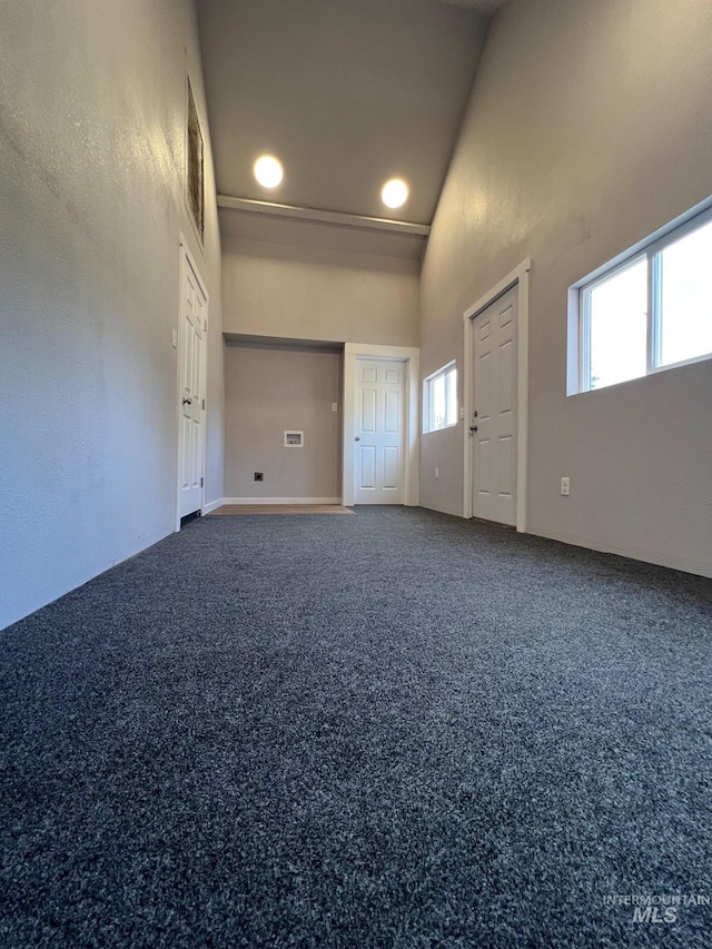 unfurnished room featuring a high ceiling, carpet flooring, and visible vents