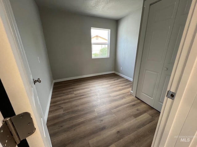 unfurnished bedroom featuring baseboards, a textured ceiling, and wood finished floors