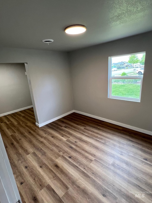 spare room with baseboards and wood finished floors