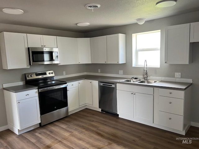kitchen with visible vents, white cabinetry, a sink, dark wood finished floors, and appliances with stainless steel finishes