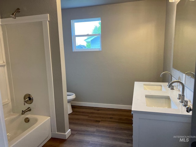 full bath with shower / tub combination, wood finished floors, a sink, baseboards, and toilet