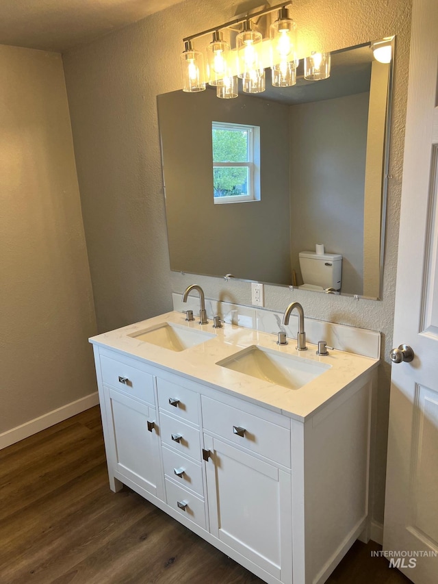 bathroom featuring a sink, a textured wall, toilet, and wood finished floors
