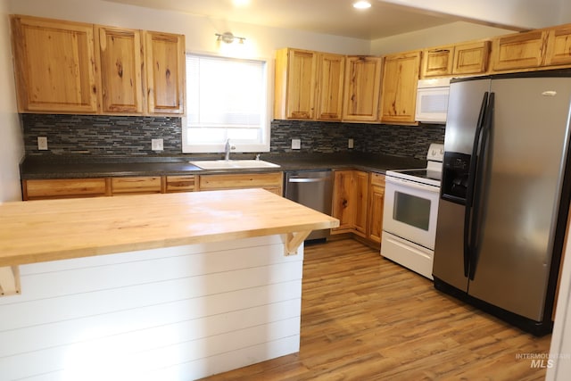 kitchen with wood counters, sink, decorative backsplash, light wood-type flooring, and stainless steel appliances