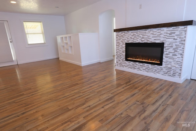 unfurnished living room featuring a tiled fireplace and dark wood-type flooring