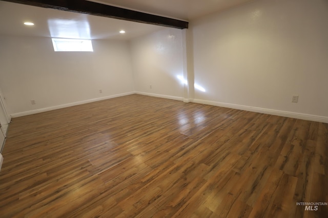 unfurnished room with dark hardwood / wood-style flooring and beamed ceiling