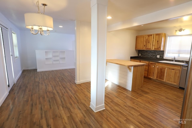 kitchen featuring dishwasher, backsplash, dark wood-type flooring, wooden counters, and hanging light fixtures