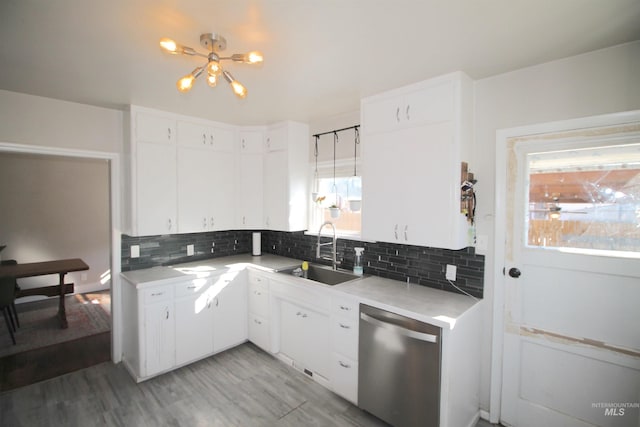 kitchen with light countertops, backsplash, white cabinetry, a sink, and dishwasher