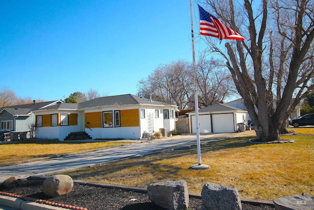 view of front of property featuring a front yard, a detached garage, and an outbuilding