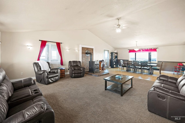 living area with vaulted ceiling, a wood stove, carpet floors, and ceiling fan