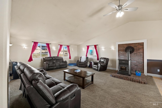 living room featuring carpet, lofted ceiling, a wood stove, and a ceiling fan