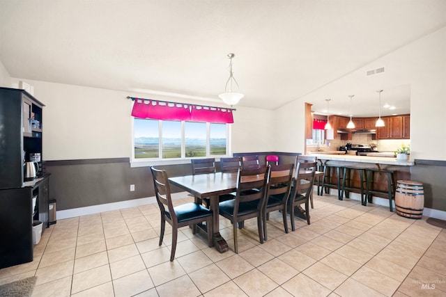 dining space featuring light tile patterned floors, baseboards, and lofted ceiling