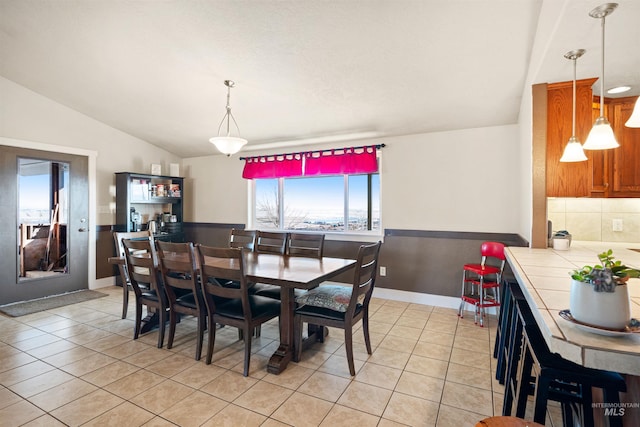 dining room featuring light tile patterned floors, baseboards, and vaulted ceiling