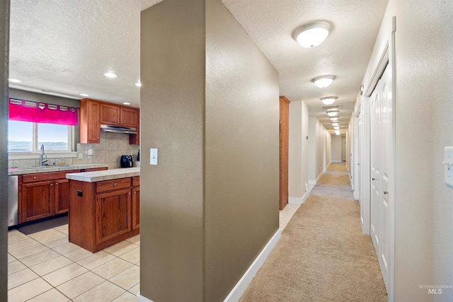 hall with baseboards, light carpet, light tile patterned flooring, a textured ceiling, and a sink