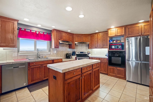 kitchen with tile countertops, light tile patterned floors, appliances with stainless steel finishes, and a sink