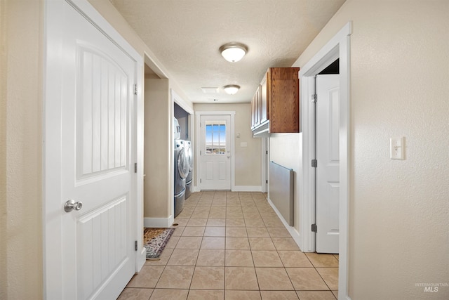 hallway with baseboards, separate washer and dryer, light tile patterned flooring, and a textured ceiling