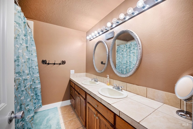 bathroom featuring a textured ceiling, double vanity, tile patterned flooring, and a sink