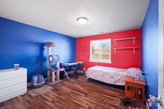 bedroom featuring visible vents, a textured ceiling, and wood finished floors