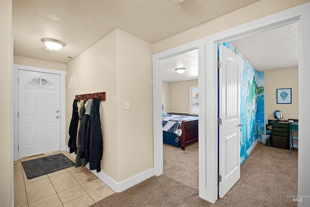 entryway featuring light tile patterned floors, light colored carpet, a textured ceiling, and baseboards