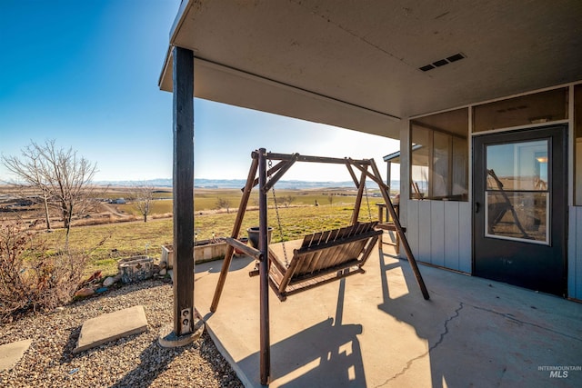 view of patio with visible vents and a rural view