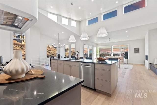 kitchen featuring dishwasher, sink, hanging light fixtures, a large island, and ceiling fan with notable chandelier