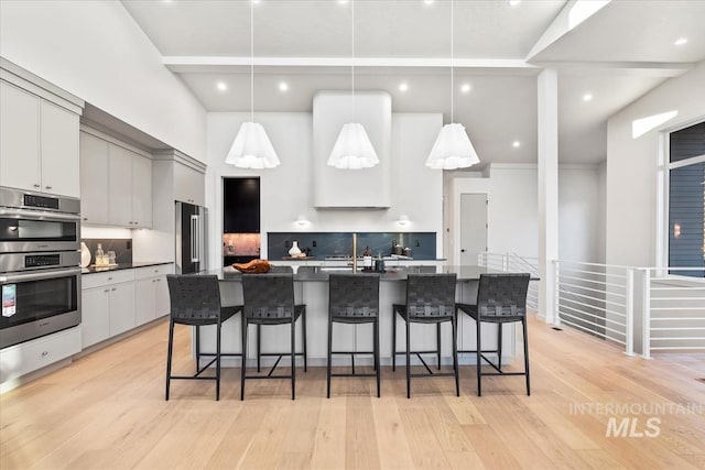 kitchen featuring tasteful backsplash, a breakfast bar, appliances with stainless steel finishes, and hanging light fixtures