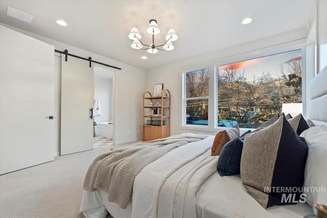 carpeted bedroom with a notable chandelier, ensuite bath, and a barn door