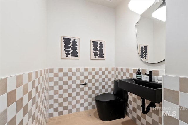 bathroom featuring sink, tile walls, and toilet