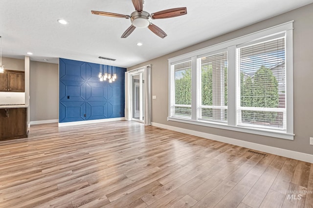 1073 W Smoky Quartz St, Kuna, ID 83634 - unfurnished living room with baseboards, light wood-style flooring, a chandelier, a ceiling fan, and recessed lighting