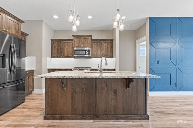 1073 W Smoky Quartz St, Kuna, ID 83634 - kitchen with refrigerator with ice dispenser, stainless steel microwave, a sink, light stone countertops, and backsplash