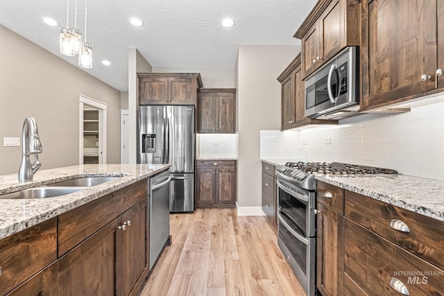 1073 W Smoky Quartz St, Kuna, ID 83634 - kitchen featuring stainless steel appliances, a sink, light wood-style floors, dark brown cabinets, and recessed lighting