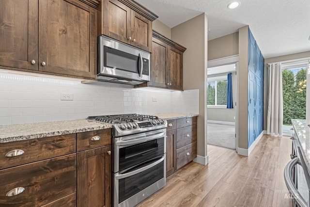1073 W Smoky Quartz St, Kuna, ID 83634 - kitchen with stainless steel appliances, light wood-style floors, baseboards, tasteful backsplash, and dark brown cabinets
