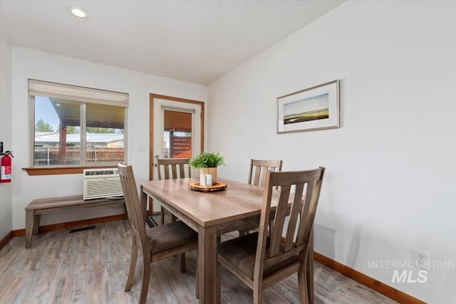 dining area featuring visible vents, baseboards, recessed lighting, an AC wall unit, and light wood finished floors