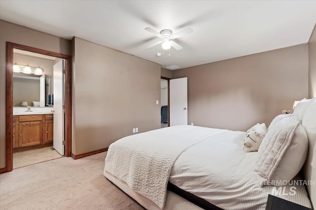 bedroom featuring visible vents, a sink, baseboards, connected bathroom, and light carpet