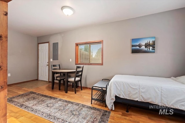 bedroom with baseboards, wood finished floors, and electric panel
