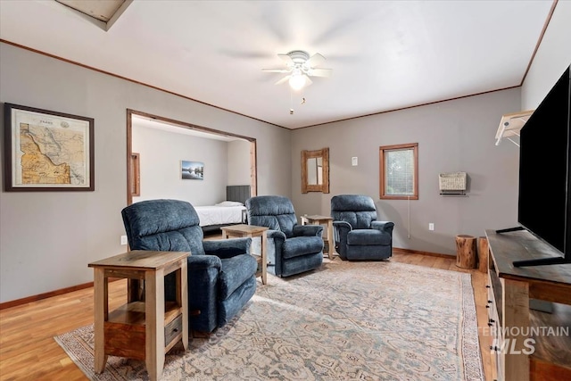 living area with ceiling fan, baseboards, and light wood finished floors