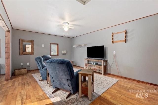 living room featuring baseboards, a ceiling fan, and light wood finished floors