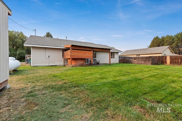 rear view of property with fence and a lawn