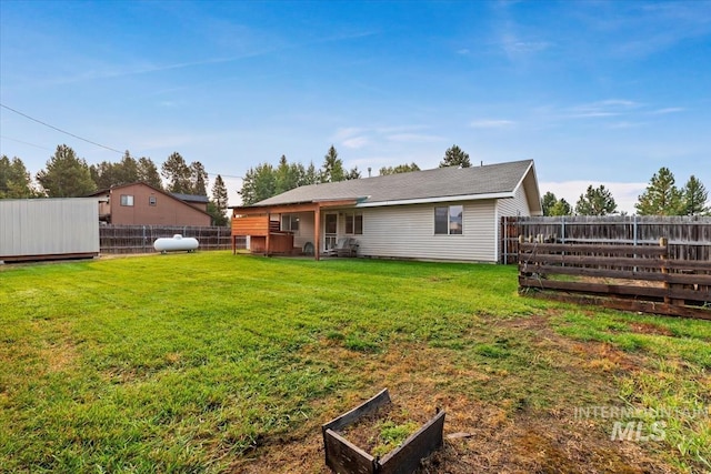 rear view of house with a lawn and a fenced backyard