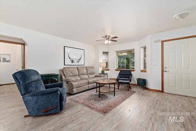 living room with baseboards, a ceiling fan, and light wood finished floors