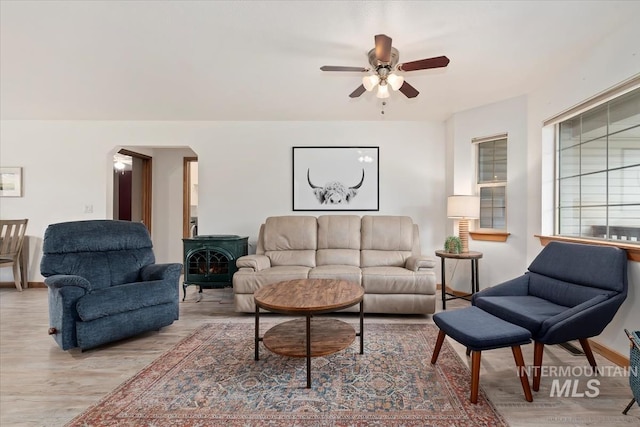 living area with arched walkways, ceiling fan, and wood finished floors