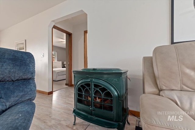 interior space with arched walkways, baseboards, wood finished floors, and a wood stove