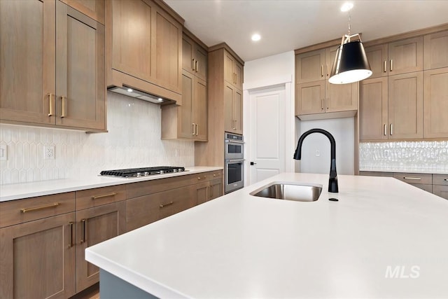 kitchen featuring a sink, hanging light fixtures, light countertops, appliances with stainless steel finishes, and backsplash